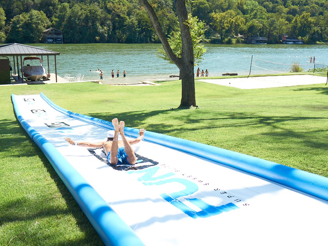 Person sliding down a large garden lawn slip and slide