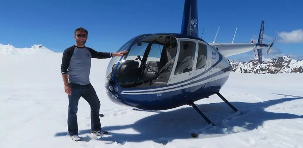 Andy Haffenden stood by a helicopter on snow up a mountain