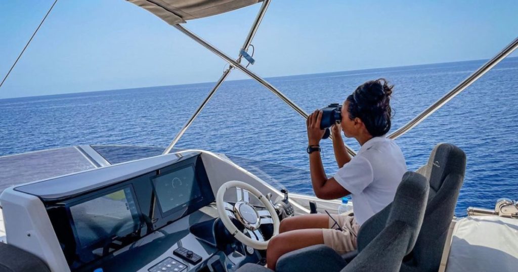 Female yacht deckhand with binoculars on watch at sea on a superyacht tender