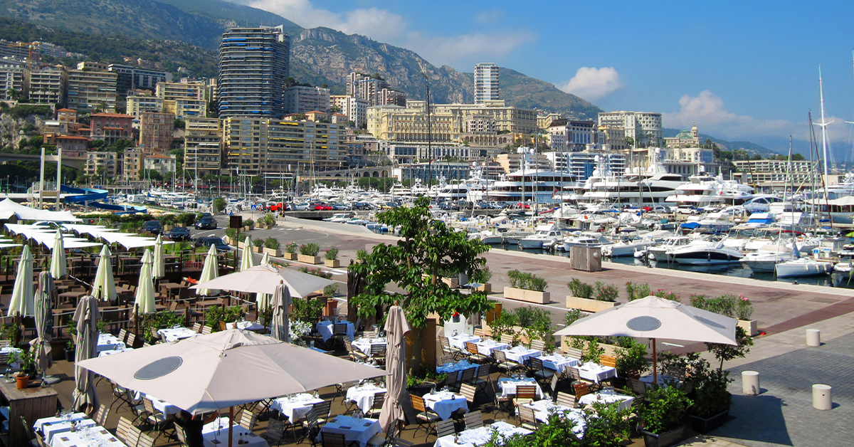 View of the harbour side restaurants in Monaco with superyachts anchored in the distance