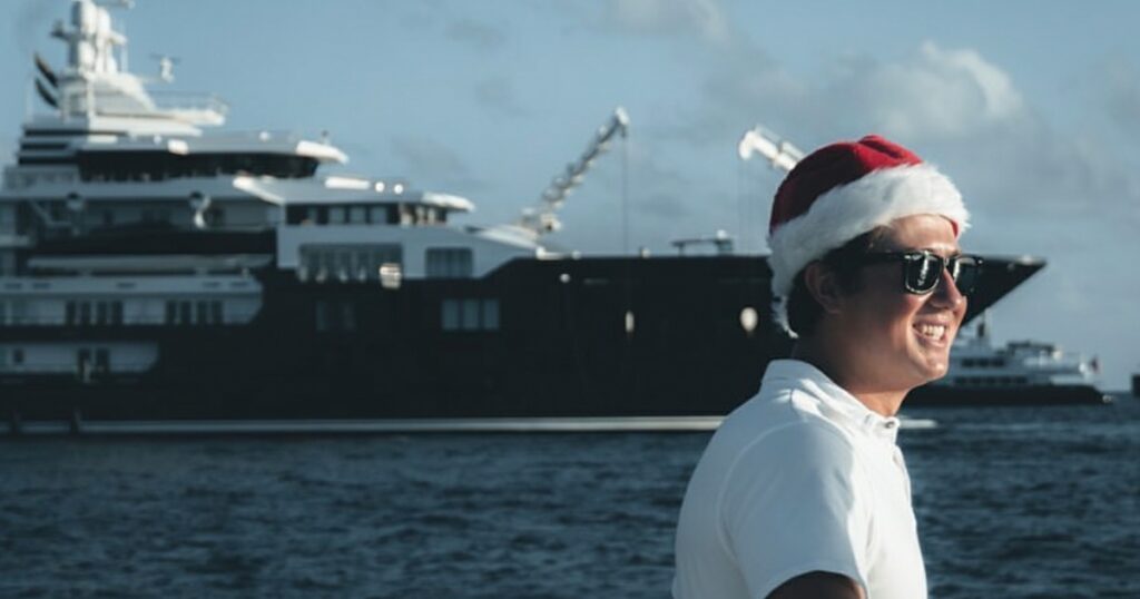 Yacht Crew member in Christmas hat with yacht in the background