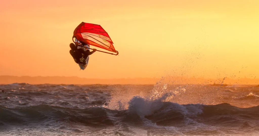 Superyacht crew member windsurfing on ocean waves