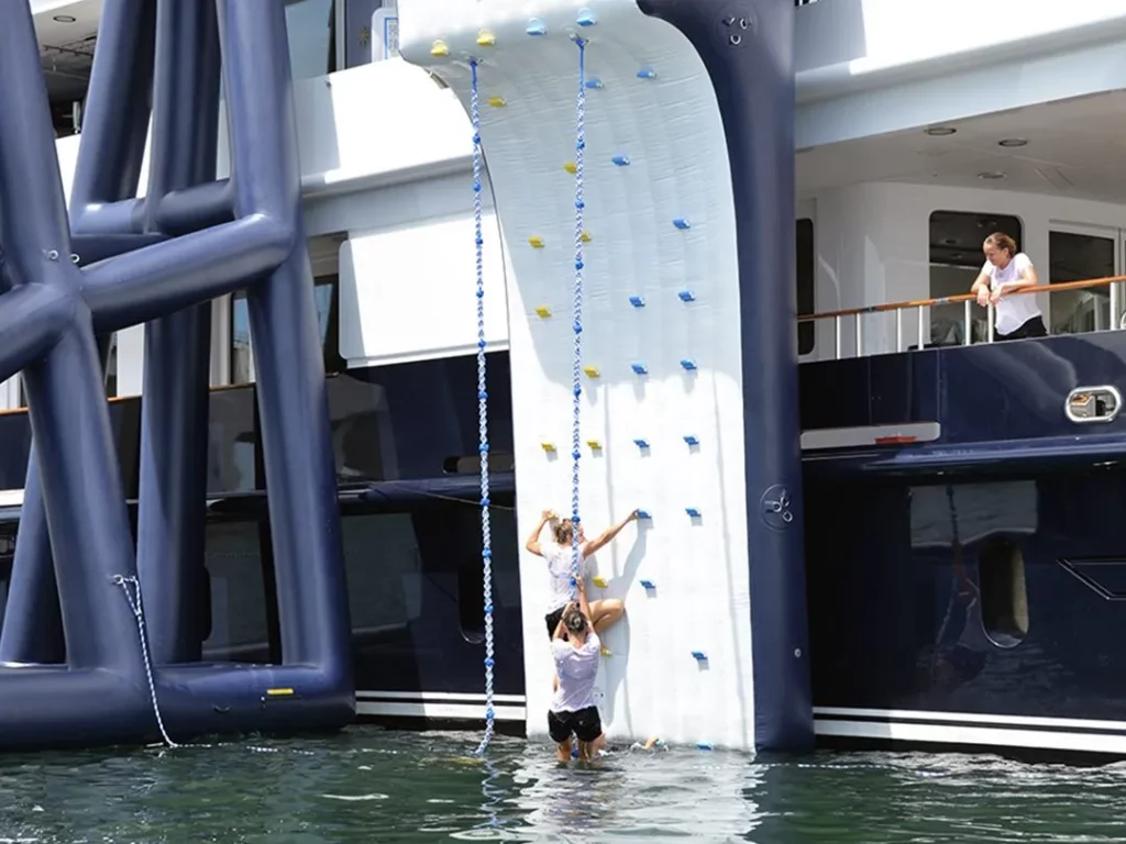 Charter guests using the Inflatable Climbing Wall on superyacht Helios