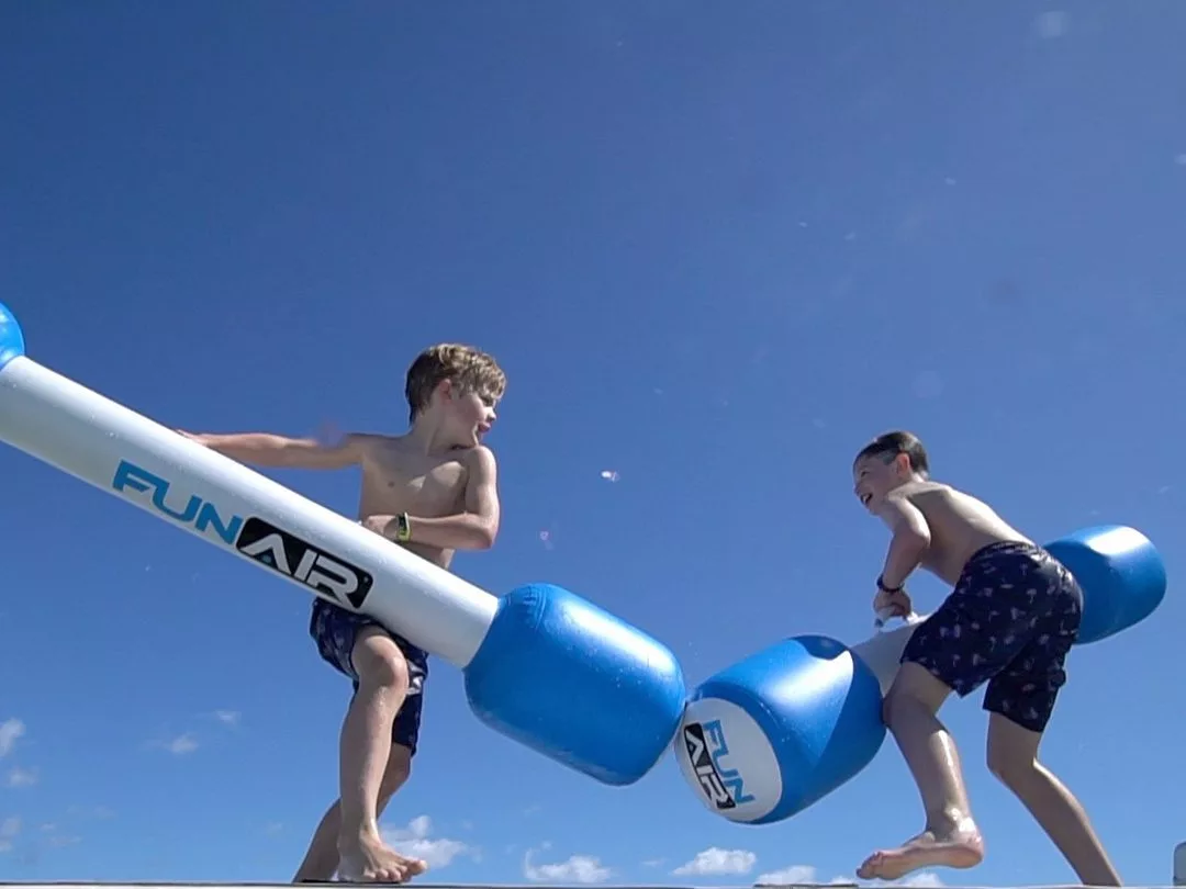Boys on a charter on a superyacht battling with Water Joust poles
