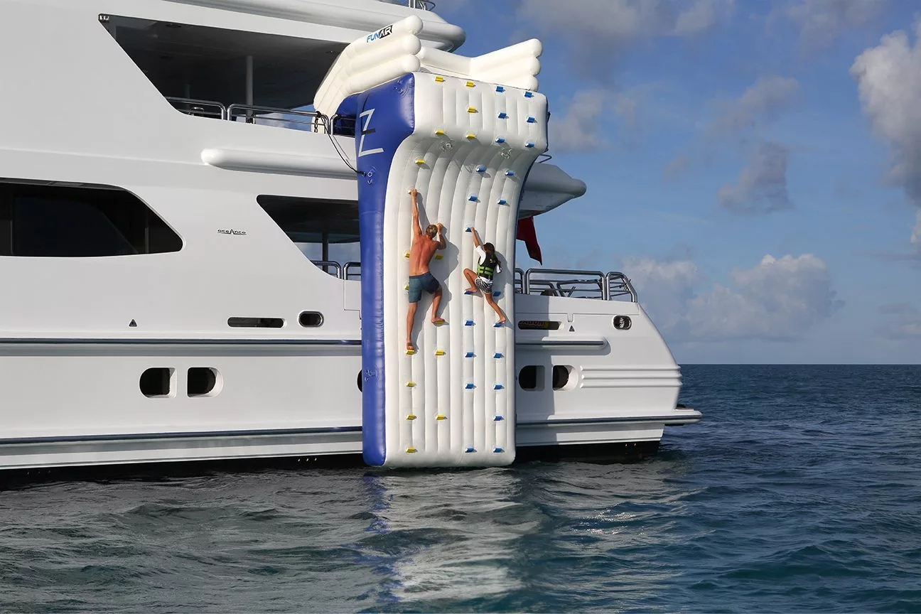 Charter yacht guests climbing on a FunAir Climbing Wall on MY Lazy Z