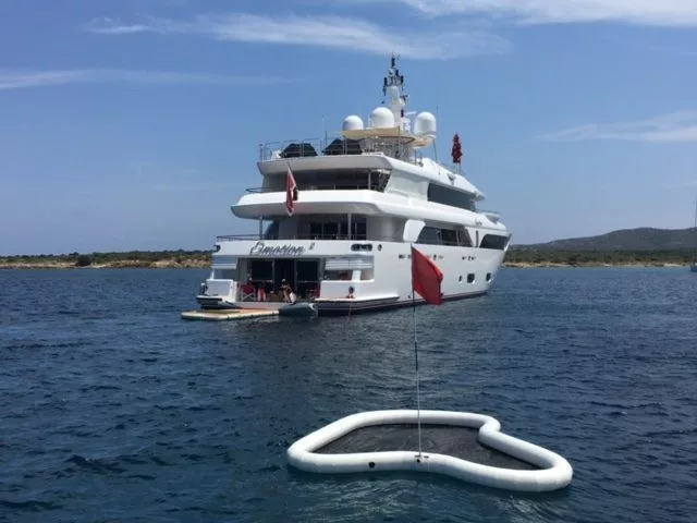 Close up of the Yacht Golf Floating Green with a superyacht in the background