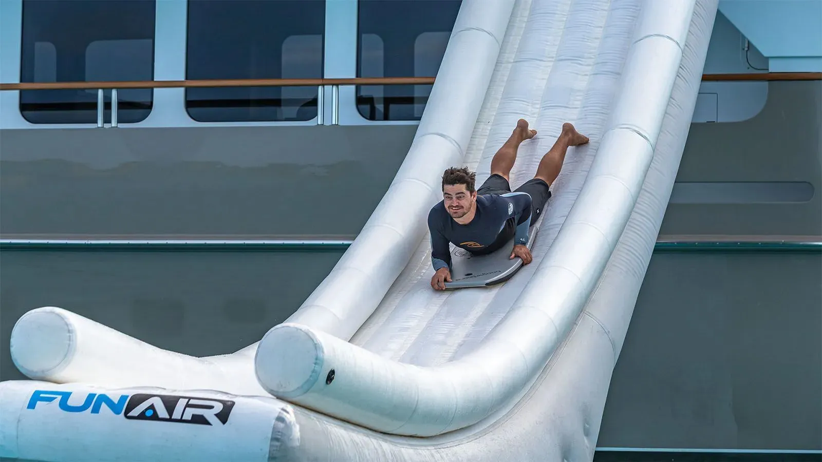 Superyacht charter guest on a body board sliding down the Yacht Slide on MY Zeal