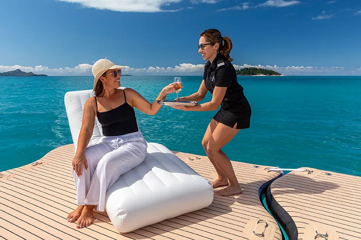 Wave Lounger female yacht crew serving drink to charter guest