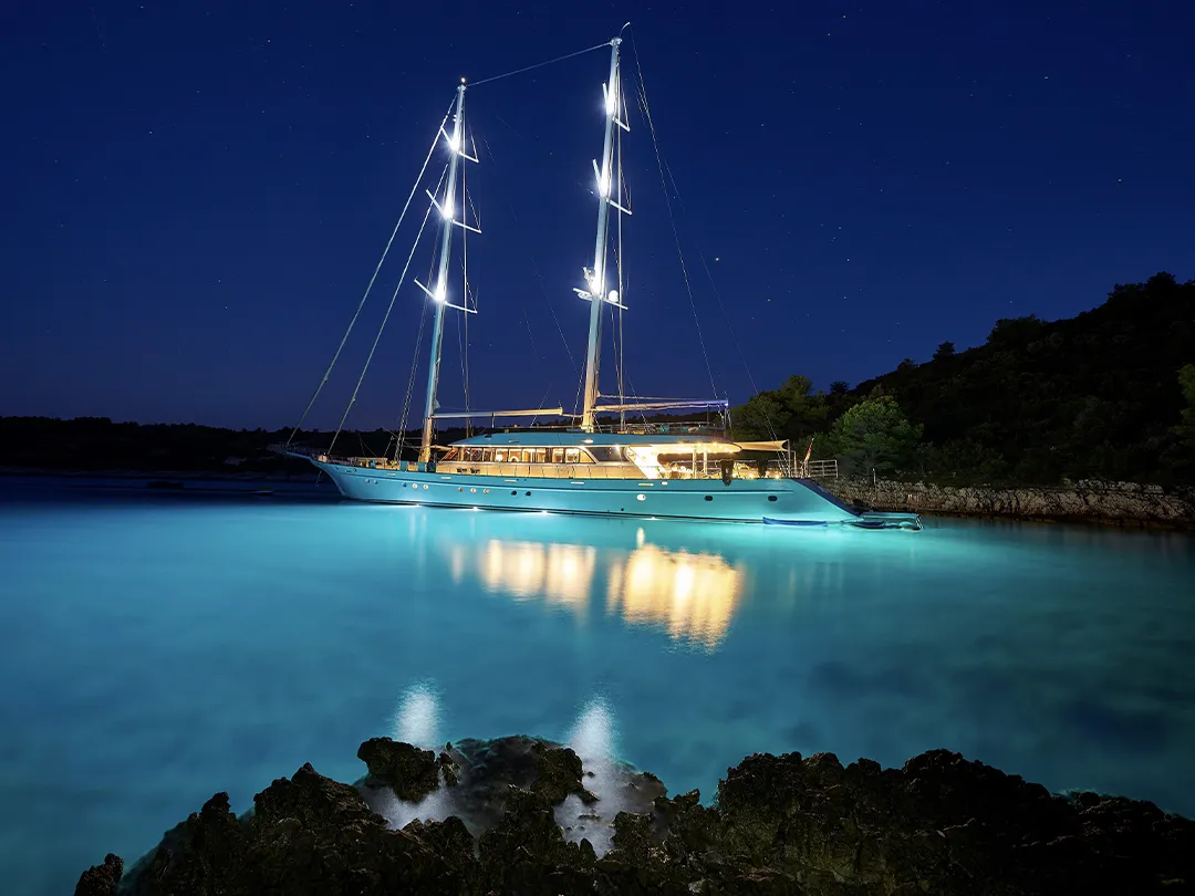 Luxury sailing yacht in blue water at night