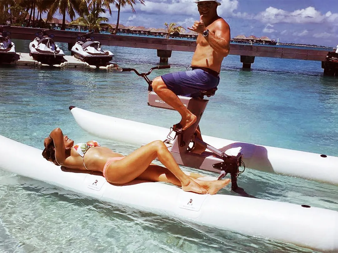Man sat on a Schiller Bike with woman sunbathing on the float