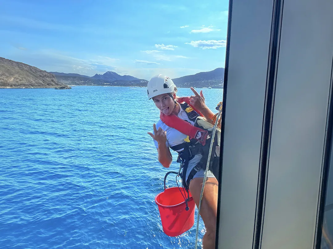 Superyacht crew member cleaning the exterior of a charter yacht