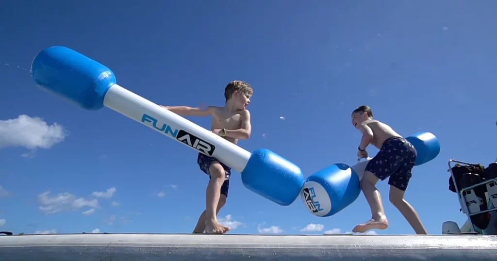 Two young charter guests using FunAir Water Joust during a luxury yacht vacation
