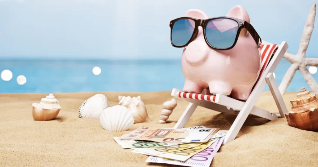 image of a piggy bank in a deck chair on a beach with money and sea shells